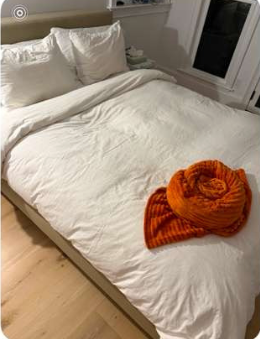 Freshly made bed with a decorative rolled towel